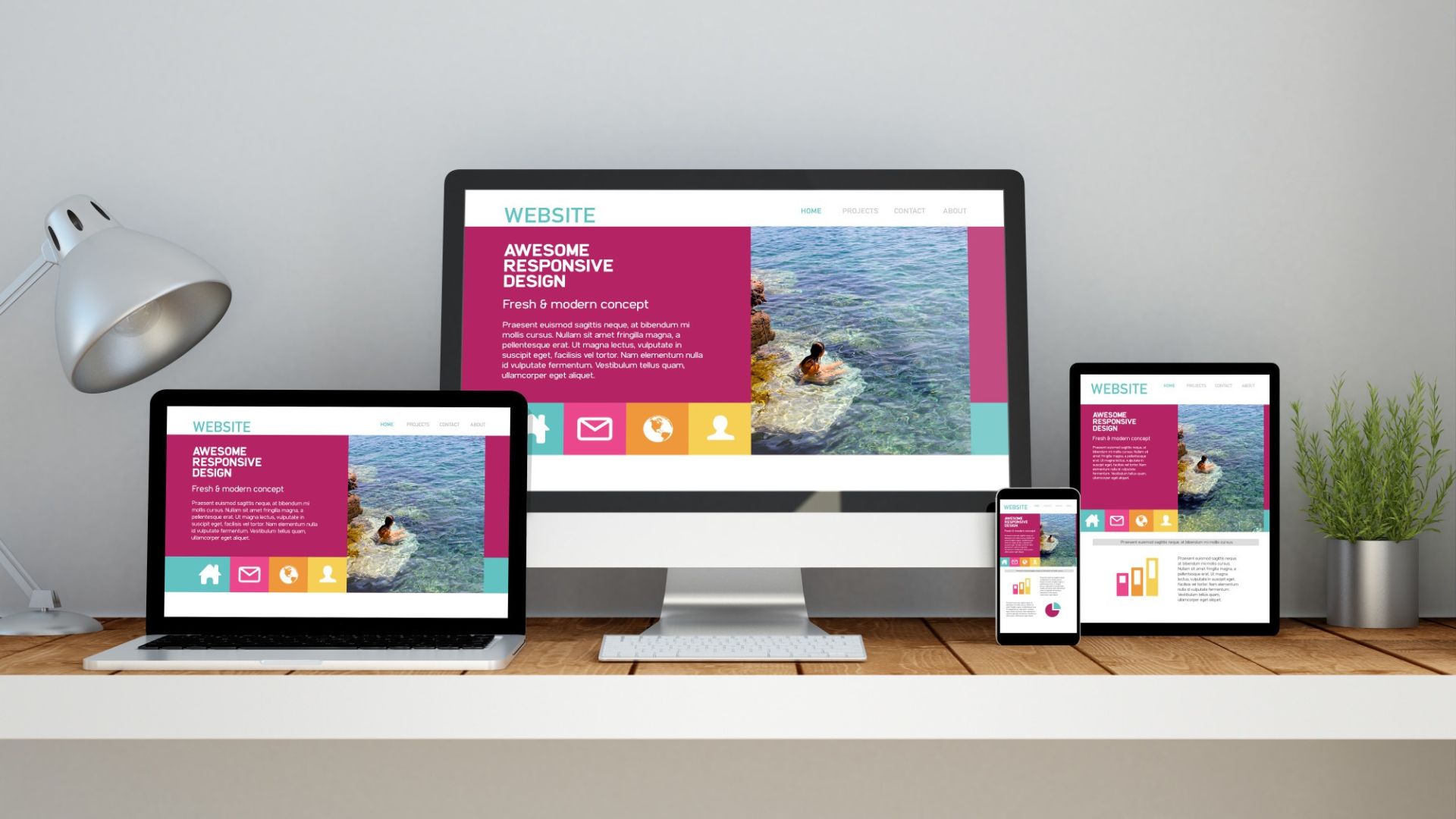 A website with colorful blocks and a swimming dog photo is displayed on a desktop, laptop, tablet, and smartphone, all on a wooden desk with a lamp and plant.